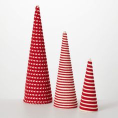 three red and white striped christmas trees sitting on top of a table next to each other