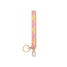 a pink and yellow keychain with an orange flower print on the front, hanging from a gold metal hook