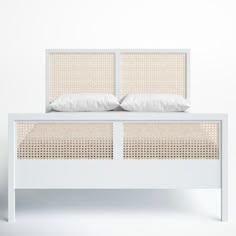 a white bed with wicker headboard and two pillows on the top of it