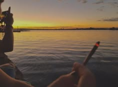 a person sitting on a boat with a glass of wine in their hand while the sun sets