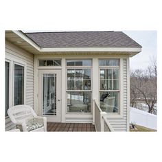 a white chair sitting on top of a wooden floor next to a window covered porch