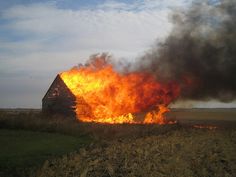 a barn on fire in an open field