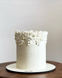 there is a white cake with flowers on the top and bottom layer, sitting on a wooden table