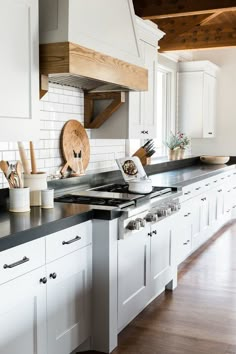 a kitchen with white cabinets and black counter tops is pictured in this image, there are wooden utensils on the stove