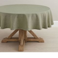 a round table with a green cloth on it's top and two wooden legs