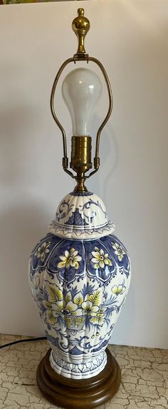 a blue and white vase sitting on top of a wooden table next to a lamp