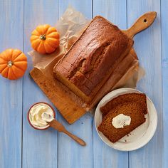 a loaf of bread sitting on top of a wooden cutting board next to a bowl of whipped cream