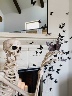 a skeleton sitting in front of a fire place with butterflies flying around it and a mirror on the wall