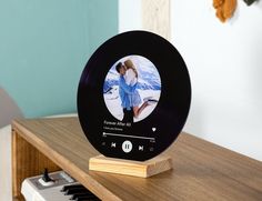 an alarm clock sitting on top of a wooden table next to a keyboard and wall