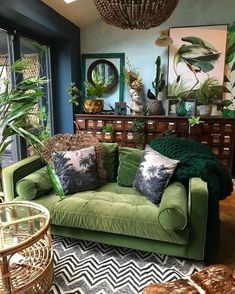 a living room filled with green furniture and lots of plants on top of the couch