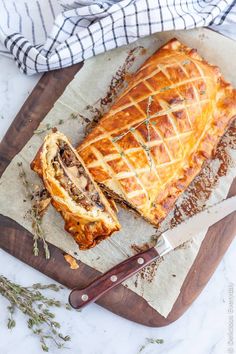 a meat and vegetable pie on a cutting board with a knife next to it, ready to be eaten