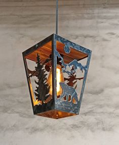 a light hanging from the ceiling with animals and trees on it's glass panels