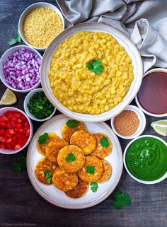 several bowls filled with different types of food on top of a wooden table next to sauces and condiments