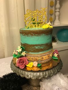 there is a cake that has been decorated with flowers on the top and letters written in gold