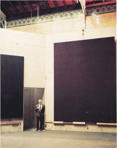 a man in a suit standing next to two large black doors with one door open