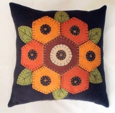 a black pillow with an orange and yellow flower design on the front, sitting on a white surface