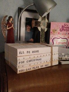 a stack of books sitting on top of a wooden table next to a mirror and angel figurine