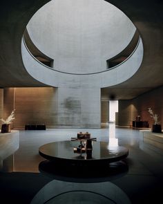 an empty room with tables and vases on the floor in front of a circular window