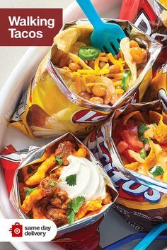 a bowl filled with lots of tacos next to two blue plastic spoons on top of a white plate