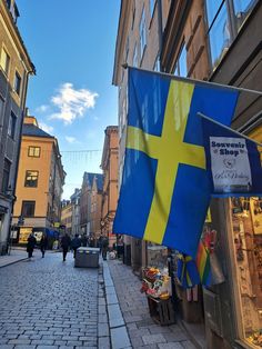 a flag hanging on the side of a building next to people walking down a street