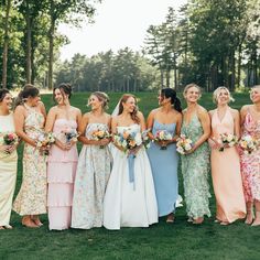 a group of women standing next to each other on top of a lush green field