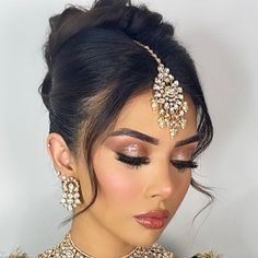 a woman with makeup and jewelry on her face, wearing a headpiece in gold