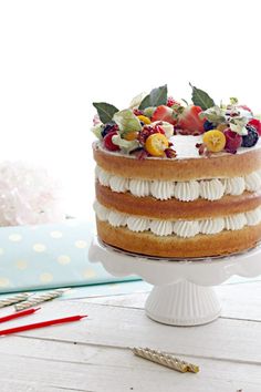 a cake sitting on top of a white cake plate covered in fruit and veggies