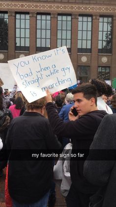 a group of people holding signs in front of a building with words written on them