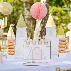 a table topped with donuts covered in frosting next to a castle shaped cake