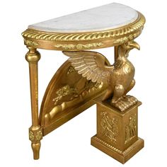 a gold and white marble topped table with an eagle on it's side stand