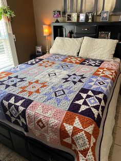 a bed with a quilt on top of it in a bedroom next to a window