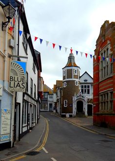 an empty street with buildings on both sides and bunting strung from the building's roof