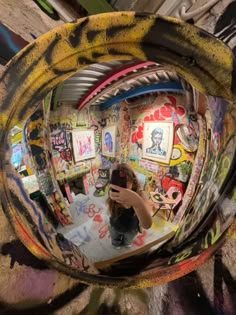 a person taking a selfie in a mirror with graffiti on the wall behind them