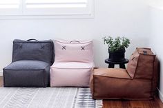 three different colored bean bags sitting next to each other on a rug in front of a window