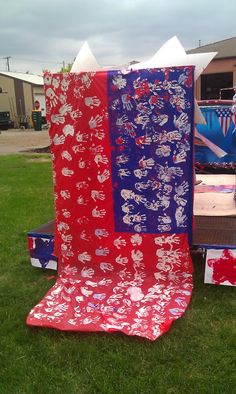 a red, white and blue blanket sitting on top of a picnic table in the grass