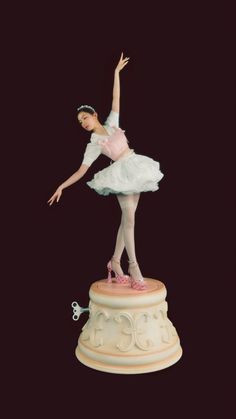 a figurine of a ballerina on top of a pedestal with her arms in the air