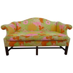 an upholstered couch with pink and green flowers on the back, against a white background