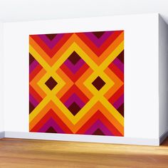 an orange, red and yellow pattern on a white wall next to a wooden floor