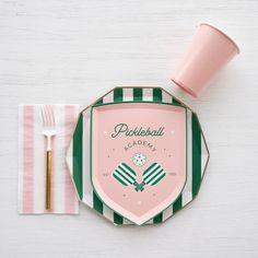 a pink and green striped plate with matching utensils sits on a white table