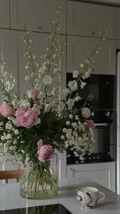 a vase filled with pink and white flowers on top of a kitchen counter next to an oven