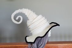 a white and black knitted hat on top of a wooden table next to a wall