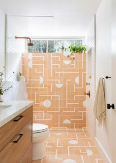 a bathroom with orange and white tiles on the walls