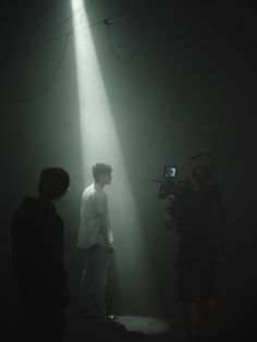 two people standing in front of a camera on a dark stage with light coming from behind them