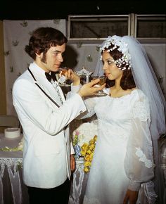 a man in a tuxedo feeding a woman a piece of cake