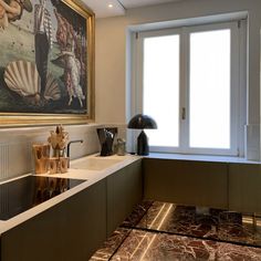 a kitchen with marble counter tops and an art work on the wall above it's sink