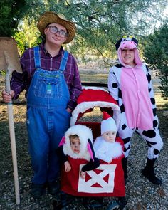 two children dressed up in costumes standing next to an adult and child on a wagon