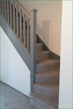 the stairs are made of carpet and have white railings on each side, along with gray carpet