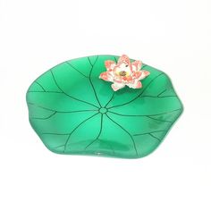 a green glass bowl with a pink flower on it