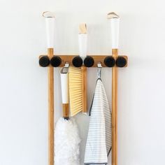 a wooden rack with three different types of cleaning supplies hanging from it's sides