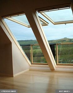 an empty room with large windows and wooden flooring on both sides, looking out onto the countryside